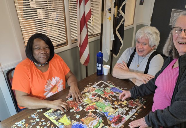 Members working on a jigsaw puzzle together at Aging Well Inc.
